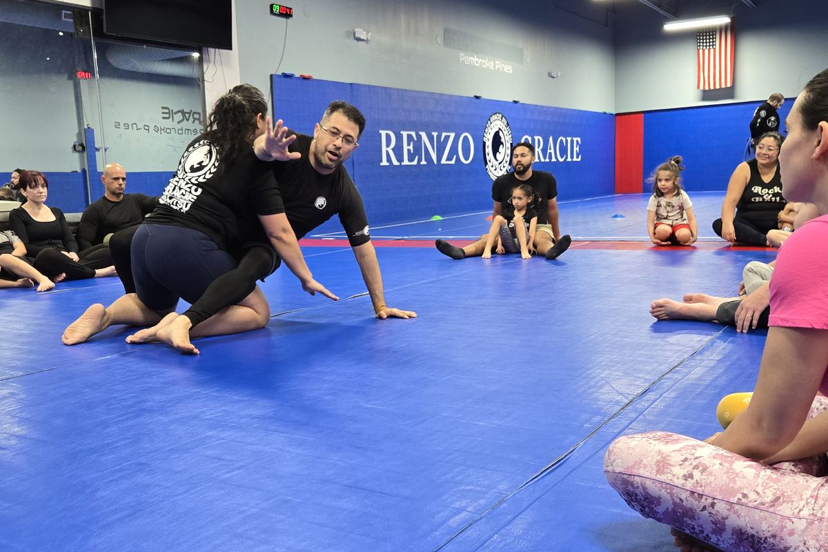 Professor Sean demonstrating a technique while parents and kids watch from the mat