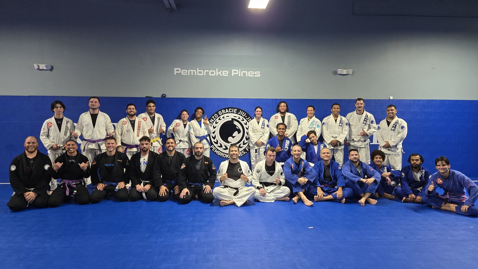 Students and coaches of Renzo Gracie Pembroke Pines in front of the academy crest